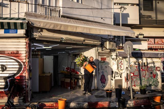 A man carries a bucket filled with flowers at Carmel market in Tel Aviv, on March 6, 2026. Israel's military on March 6 said that Iran had launched cluster bombs "multiple times" since the start of the war that began with a US-Israeli attack on the Islamic republic last week. (Photo by OLYMPIA DE MAISMONT / AFP)