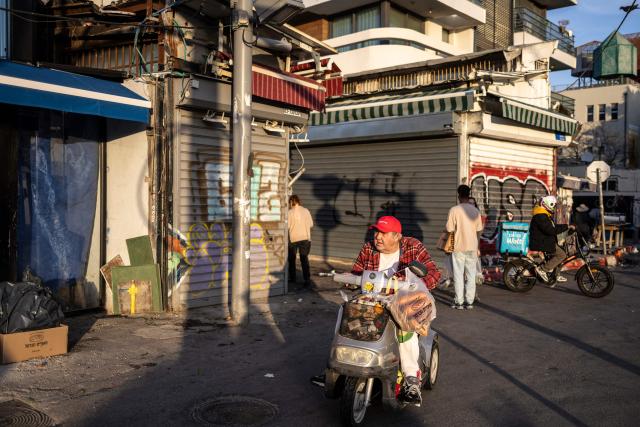 A man rides a mobility scooter with shopping bags past closed shops at Carmel market in Tel Aviv, on March 6, 2026. Israel's military on March 6 said that Iran had launched cluster bombs "multiple times" since the start of the war that began with a US-Israeli attack on the Islamic republic last week. (Photo by OLYMPIA DE MAISMONT / AFP)