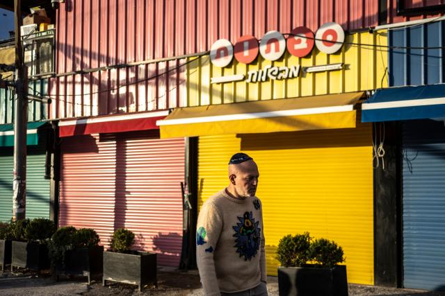 A man walks past closed shops at Carmel market in Tel Aviv, on March 6, 2026. Israel's military on March 6 said that Iran had launched cluster bombs "multiple times" since the start of the war that began with a US-Israeli attack on the Islamic republic last week. (Photo by OLYMPIA DE MAISMONT / AFP)