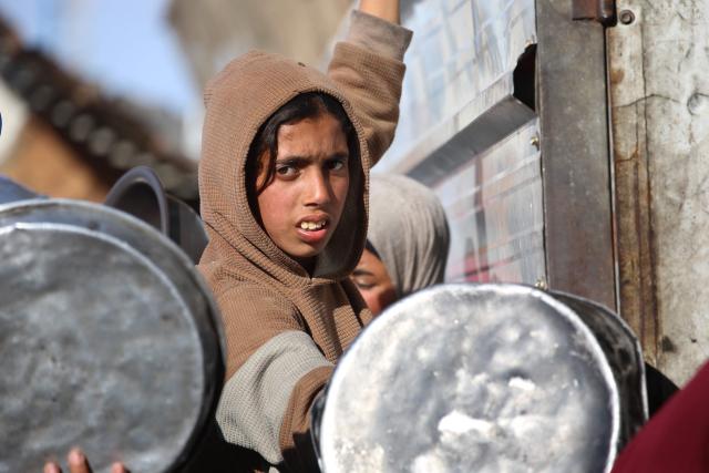 A displaced Palestinian child jostles for food at a food bank in Khan Yunis, in the south of the Gaza Strip on March 6, 2026. The majority of Gaza's 2.4 million people have been displaced, often multiple times, by the war that began with Hamas's attack on southern Israel on October 7, 2023. With displaced families living in tented camps, with serious concerns raised over their living conditions. (Photo by Bashar Taleb / AFP)
