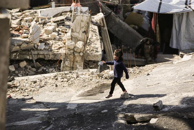 A displaced Palestinian girl plays on the roof of a collapsed building destroyed during Israeli military bombardment of the Gaza Strip, in Khan Yunis, in the south of the Gaza Strip on March 6, 2026. The majority of Gaza's 2.4 million people have been displaced, often multiple times, by the war that began with Hamas's attack on southern Israel on October 7, 2023. With displaced families living in tented camps, with serious concerns raised over their living conditions. (Photo by Bashar Taleb / AFP)