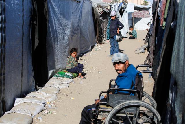Displaced Palestinians who lost their homes and businesses during Israeli military bombardment of the Gaza Strip, sit outside their tents in Khan Yunis, in the south of the Gaza Strip on March 6, 2026. The majority of Gaza's 2.4 million people have been displaced, often multiple times, by the war that began with Hamas's attack on southern Israel on October 7, 2023. With displaced families living in tented camps, with serious concerns raised over their living conditions. (Photo by Bashar Taleb / AFP)