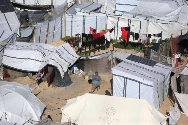 A man sit in the sun surrounded by tents are set up to house displaced Palestinians who lost their homes and businesses during Israeli military bombardment of the Gaza Strip, in Khan Yunis, in the south of the Gaza Strip on March 6, 2026. The majority of Gaza's 2.4 million people have been displaced, often multiple times, by the war that began with Hamas's attack on southern Israel on October 7, 2023. With displaced families living in tented camps, with serious concerns raised over their living conditions. (Photo by Bashar Taleb / AFP)