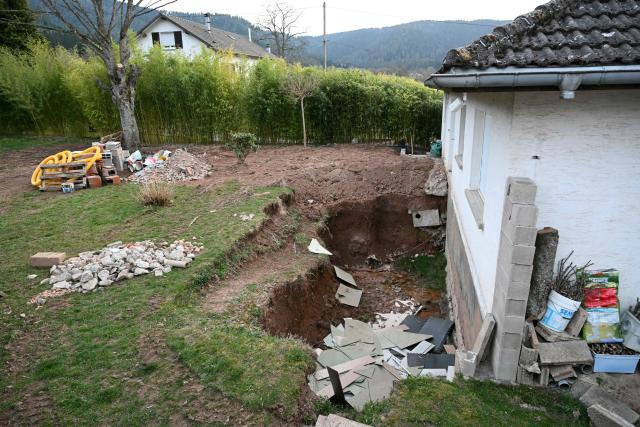 This photograph shows the excavated garden belonging to Liliane Coinchelin's youngest son in Saint-Michel-sur-Meurthe, eastern France, on March 6, 2026, as part of the search for the body of Liliane Coinchelin whose son is suspected to have held his mother captive for several months. A 39-year-old man has been charged with torture and barbaric acts resulting in the death of his mother, who died at least three years ago, the public prosecutor in Epinal, in the Vosges region, announced on March 6, 2026. The deceased woman's eldest son, aged 45, and his partner, aged 40, have been charged with complicity in acts of torture and barbarity resulting in death, unlawful confinement by an organised gang, and organised fraud. An investigation into her disappearance was launched after the mayor of Saint-Michel-sur-Meurthe reported on January 28, 2026 that Liliane Coinchelin, a resident of this village of some 1,700 inhabitants near Saint-Die-des-Vosges, had been missing for at least three years. (Photo by SEBASTIEN BOZON / AFP)