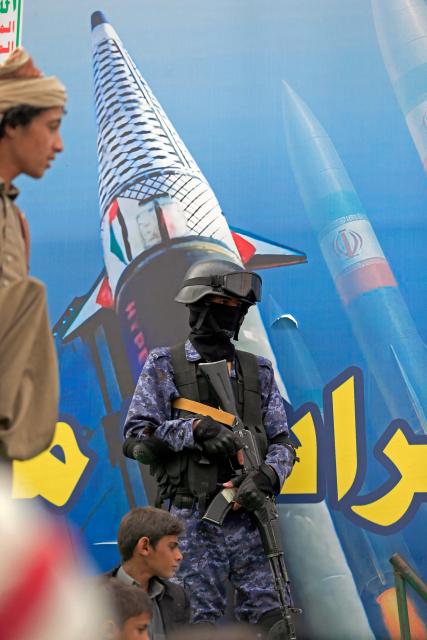 A security personnel stands guard as Houthi supporters gather during a rally in solidarity with Iran and Lebanon, amid the US-Israeli conflict with Iran, in the Yemeni capital Sanaa on March 6, 2026. The US president on March 6, demanded Iran's "unconditional surrender" as the only acceptable outcome to end hostilities, while promising to help rebuild the country's economy if Tehran complied. (Photo by Mohammed HUWAIS / AFP)