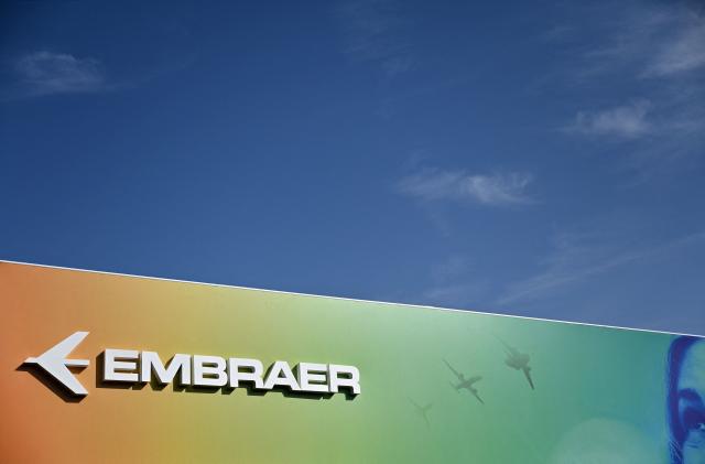 (FILES) A logo is pictured on the Embraer stand at the Farnborough Airshow, in Farnborough, on July 19, 2022. Brazilian aircraft manufacturer Embraer said on March 6, 2026 it had achieved its highest ever revenues in 2025, but US tariffs cut deeply into its profits. The company paid $80 million in tariffs to the United States, a major client for commercial and executive aircraft, and net profit fell 45 percent compared to 2024. (Photo by JUSTIN TALLIS / AFP)