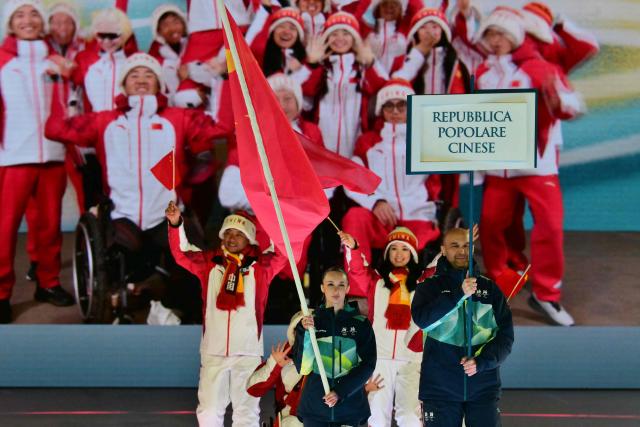 Members of China's delegation parade as volunteers hold a flag and a placard during the delegation parade of the Milano Cortina 2026 Winter Paralympic Games opening ceremony at Arena di Verona in Verona on March 6, 2026. (Photo by Stefano RELLANDINI / AFP)