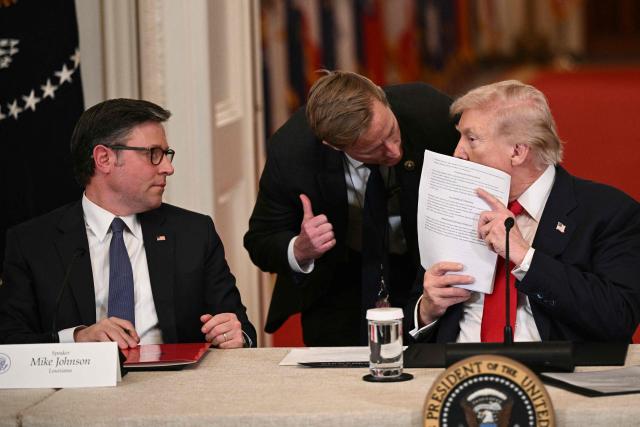 US Speaker of the House Mike Johnson (R-LA) looks on as US President Donald Trump speaks with a secret service agent during a roundtable to "save college sports" in the East Room of the White House in Washington, DC, on March 6, 2026. (Photo by Brendan SMIALOWSKI / AFP)