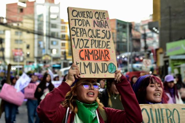 A young women shows a sign that reads in Spanis "I want every girl to know that her voice can change the world," during a march against government on the eve of International Women's Day in La Paz on March 6, 2026. The International Women's Rights Day will fall on March 8, 2026. (Photo by Jorge BERNAL / AFP)