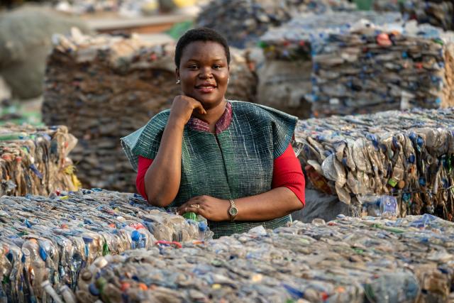 Rita Idehai, founder of Ecobarter, poses for a photograph between stacked bales of compressed plastic waste at her facility in Abuja in Abuja on March 4, 2026. Rita Idehai launched her company, Ecobarter, in Abuja in 2018, building on an idea she developed in 2017 to turn waste into resources.
She also created the Waste Resource Empowerment Program, which helps women in local communities turn plastic waste into handwoven materials used to produce bags, clothing, and other fashion items.
Through her work, plastics that would otherwise contribute to environmental pollution are repurposed and reintroduced into society as fashionable accessories. Ecobarter also encourages people to exchange recyclable waste for useful items, creating a system that rewards responsible waste disposal while helping reduce plastic pollution in local communities. (Photo by Light Oriye Tamunotonye / AFP)