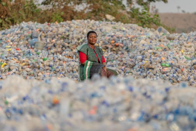 Rita Idehai, founder of Ecobarter, wearing a jacket and trousers made with plabric, is seen seated between large stockpiles of plastic bottles at her facility in Abuja in Abuja on March 4, 2026. Rita Idehai launched her company, Ecobarter, in Abuja in 2018, building on an idea she developed in 2017 to turn waste into resources.
She also created the Waste Resource Empowerment Program, which helps women in local communities turn plastic waste into handwoven materials used to produce bags, clothing, and other fashion items.
Through her work, plastics that would otherwise contribute to environmental pollution are repurposed and reintroduced into society as fashionable accessories. Ecobarter also encourages people to exchange recyclable waste for useful items, creating a system that rewards responsible waste disposal while helping reduce plastic pollution in local communities. (Photo by Light Oriye Tamunotonye / AFP)