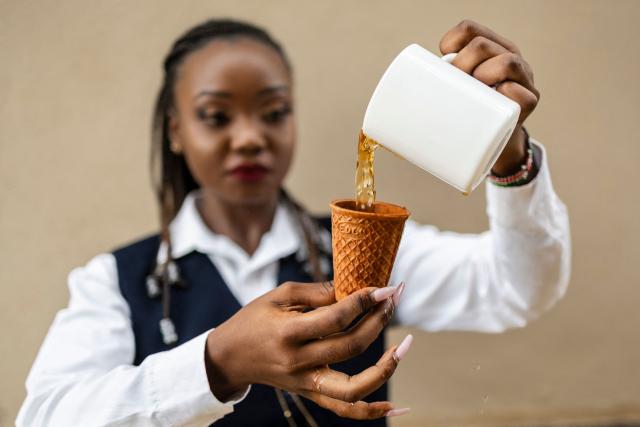Kenyan innovator and ecopreneur, Sheryl Mboya, 26, demonstrates the superior structural integrity to hold hot-liquid of one of her innovations, an edible cup, an idea born of her dislike of plastic pollution in Nairobi on March 6, 2026. Christened 'snackuit', the law graduate's patented edible tableware is her answer to single-use plastics pollution and is alot safer for the general environment due to it's biodegradability.Developed under GreenX Telemechanics Limited, a technology and innovation developer whose core objective is to come up with innovative solutions such as Snackuit, that not only address challenges mankind face but also contribute to climate action. (Photo by Tony KARUMBA / AFP)