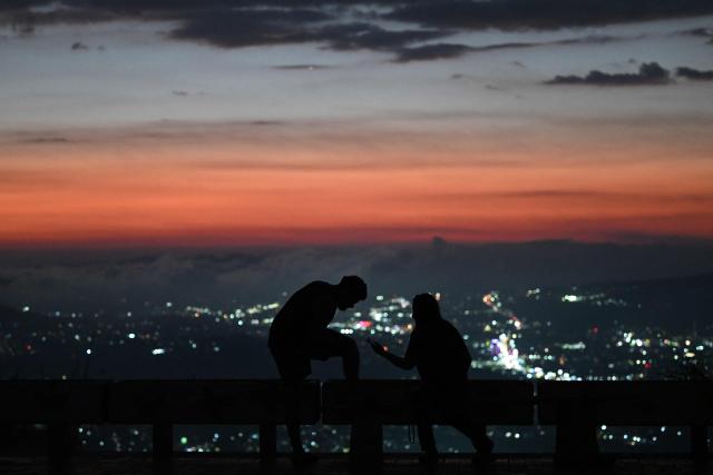 People enjoy the sunset from Cerro San Jacinto in Soyapango, El Salvador on March 6, 2026. (Photo by Marvin RECINOS / AFP)
