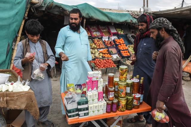 People buy food items at a roadside stall in the Pakistan–Iran border town of Taftan, Balochistan province, on March 6, 2026. (Photo by Banaras KHAN / AFP)