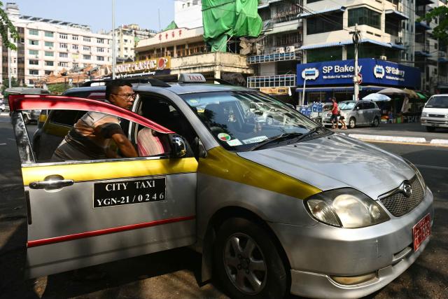 A taxi driver waits for passengers on the first day of the implementation of an "odd-even" vehicle numbering system in Yangon on March 7, 2026. Myanmar's junta announced half of private vehicles will be ordered off the roads each day, based on licence plate numbers, in order to conserve fuel due to the war in the Middle East. Myanmar imports 90 percent of its fuel oil, according to 2024 figures, and has long suffered from a fragile energy supply chain owing to the civil war consuming the country since the military staged a coup five years ago. (Photo by Sai Aung MAIN / AFP)
