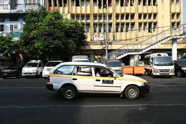 A passenger rides in a taxi on the first day of the implementation of an "odd-even" vehicle numbering system in Yangon on March 7, 2026. Myanmar's junta announced half of private vehicles will be ordered off the roads each day, based on licence plate numbers, in order to conserve fuel due to the war in the Middle East. Myanmar imports 90 percent of its fuel oil, according to 2024 figures, and has long suffered from a fragile energy supply chain owing to the civil war consuming the country since the military staged a coup five years ago. (Photo by Sai Aung MAIN / AFP)