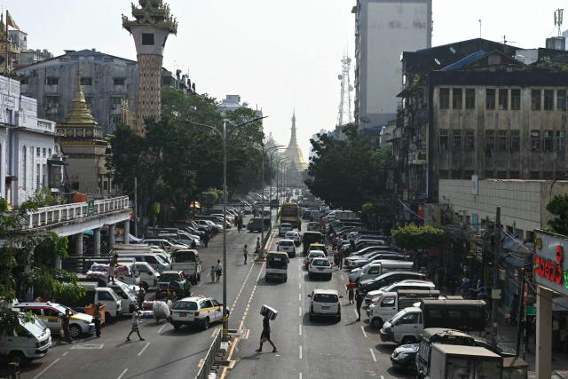 Vehicles and pedestrians are seen along a road on the first day of the implementation of an "odd-even" vehicle numbering system in Yangon on March 7, 2026. Myanmar's junta announced half of private vehicles will be ordered off the roads each day, based on licence plate numbers, in order to conserve fuel due to the war in the Middle East. Myanmar imports 90 percent of its fuel oil, according to 2024 figures, and has long suffered from a fragile energy supply chain owing to the civil war consuming the country since the military staged a coup five years ago. (Photo by Sai Aung MAIN / AFP)