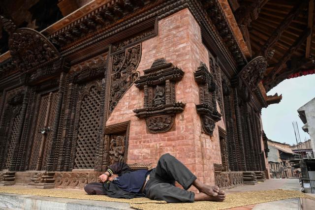 A man takes a nap outside a temple at Durbar Square in Bhaktapur near Kathmandu on March 7, 2026. Nepal's centrist party of rapper-turned-politician Balendra Shah looked set to win by a landslide in parliamentary polls, according to Election Commission trends March 7, but with counting still far to go. (Photo by Tauseef MUSTAFA / AFP)