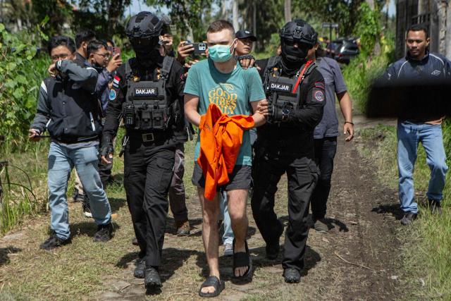 Russian national suspects  S.T. (C), 34, accused of operating a laboratory producing the synthetic drug mephedrone, is escorted by police to the house used to manufacture drugs during a crime scene reconstruction as authorities search for another foreign suspect in Gianyar, on Indonesia's resort island of Bali on March 7, 2026. (Photo by LANA PRIATNA / AFP)