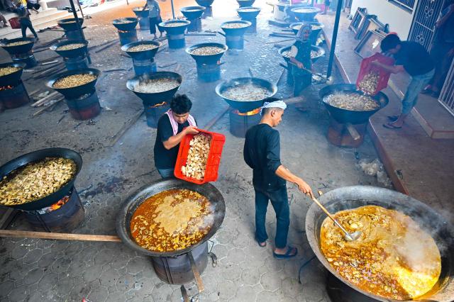 Men cook traditional curry dishes called 'kuah beulangong' in cauldrons to be shared at iftar, to commemorate the revelation of the Quran during the Muslim holy month of Ramadan, in Banda Aceh on March 7, 2026. (Photo by CHAIDEER MAHYUDDIN / AFP)