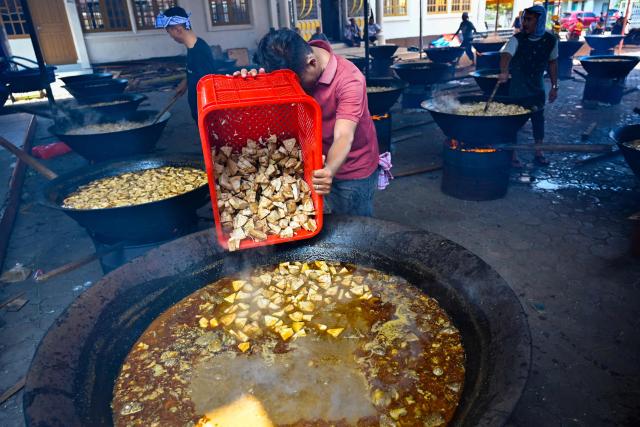 Men cook traditional curry dishes called 'kuah beulangong' in cauldrons to be shared at iftar, to commemorate the revelation of the Quran during the Muslim holy month of Ramadan, in Banda Aceh on March 7, 2026. (Photo by CHAIDEER MAHYUDDIN / AFP)