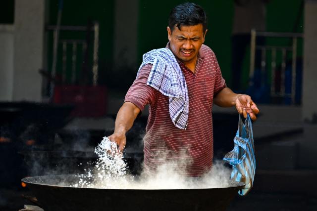A man cooks a traditional curry dish called 'kuah beulangong' in a cauldron to be shared at iftar, to commemorate the revelation of the Quran during the Muslim holy month of Ramadan, in Banda Aceh on March 7, 2026. (Photo by CHAIDEER MAHYUDDIN / AFP)