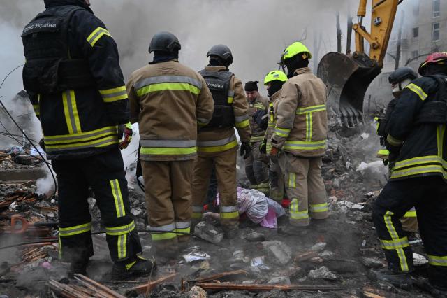 Rescuers retrieve a body from under the rubbles of a five-story residential building which was hit by a ballistic missile in Kharkiv on March 7, 2026 amid the Russian invasion of Ukraine. Russia pummelled Ukraine with drone and missile attacks overnight, killing six people and triggering air alerts across the country, officials said. The bodies of five people were found in the rubble of an apartment block in the eastern Kharkiv region, while one person was killed in the Dnipropetrovsk region. (Photo by SERGEY BOBOK / AFP)