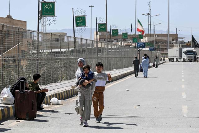 Pakistani nationals walk across the Taftan border as they return from Iran, in Balochistan province, on March 7, 2026 amid ongoing US-Israel strikes on Iran. Pakistani nationals hauled suitcases across the border from neighbouring Iran, describing missiles being launched and travel chaos as they scrambled to leave the country that the United States and Israel hit with strikes over the weekend. (Photo by Banaras KHAN / AFP)