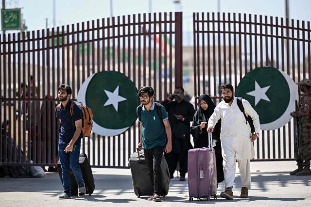 Pakistani nationals walk across the Taftan border as they return from Iran, in Balochistan province on March 7, 2026 amid ongoing US–Israel strikes on Iran. Pakistani nationals hauled suitcases across the border from neighbouring Iran, describing missiles being launched and travel chaos as they scrambled to leave the country that the United States and Israel hit with strikes over the weekend. (Photo by Banaras KHAN / AFP)