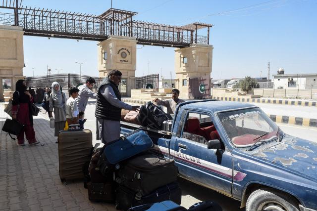 Pakistani nationals board a vehicle after crossing the Taftan border as they return from Iran, in Balochistan province on March 7, 2026 amid ongoing US-Israel strikes on Iran. Pakistani nationals hauled suitcases across the border from neighbouring Iran, describing missiles being launched and travel chaos as they scrambled to leave the country that the United States and Israel hit with strikes over the weekend. (Photo by Banaras KHAN / AFP)