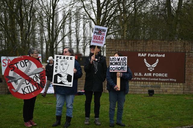 Anti-war protesters gather with placards at an entrance to RAF Fairford in south west England shortly after sunrise on March 7, 2026. Britain's Prime Minister Keir Starmer has given approval for Washington to use the bases of Diego Garcia in the Indian Ocean and RAF Fairford in south-west England to bomb Iranian missile sites, after several Gulf countries were targeted by Iranian retaliations. (Photo by JUSTIN TALLIS / AFP)