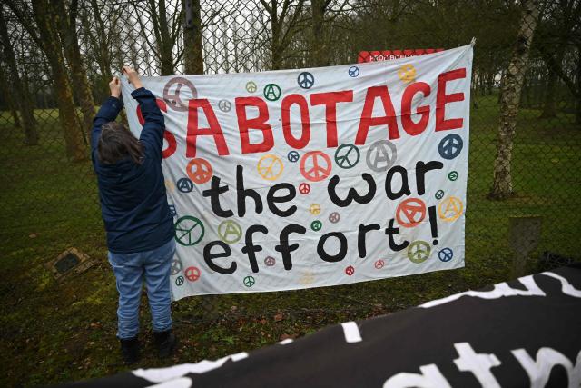 Anti-war protesters put up banners on the fencing at an entrance to RAF Fairford in south west England shortly after sunrise on March 7, 2026. Britain's Prime Minister Keir Starmer has given approval for Washington to use the bases of Diego Garcia in the Indian Ocean and RAF Fairford in south-west England to bomb Iranian missile sites, after several Gulf countries were targeted by Iranian retaliations. (Photo by JUSTIN TALLIS / AFP)