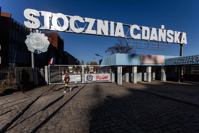 A worker walks past the gate of the historic Gdansk Shipyard  on March 6, 2026. The shipyard, known as a birthplace of the Solidarnosc trade union that led to the fall of communism in Poland in 1989, still builds some ships but today, mainly wind turbines are produced at the site. (Photo by Wojtek RADWANSKI / AFP)