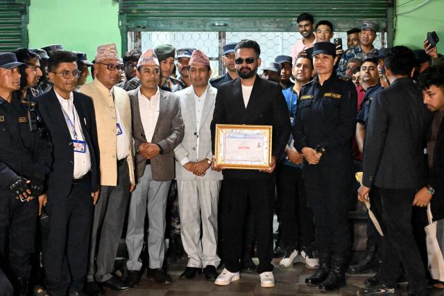 Rastriya Swatantra Party (RSP) election candidate Balendra Shah (C) poses after collecting a certificate for his victory in parliamentary elections at the counting centre in Damak in Nepal's Jhapa district on March 7, 2026. Nepal's rapper-turned-mayor Shah grinned and flashed a V for victory sign on March 7 as Election Commission officials confirmed he had defeated veteran leader KP Sharma Oli in their parliamentary constituency. (Photo by Prakash MATHEMA / AFP)