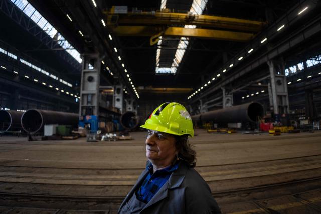 Halina Krauze, 65, a overhead crane operator, poses for a photo in the production hall of the Gdansk Shipyard in Gdansk, Poland, on March 6, 2026. "Around 70% of crane operators on construction sites today are women," Krause explains, a tradition inherited from the communist era. The shipyard, known as the birthplace of the Solidarnosc trade union that led to the fall of communism in Poland in 1989, still builds some ships but today, mainly wind turbines are produced at the site. (Photo by Wojtek RADWANSKI / AFP)