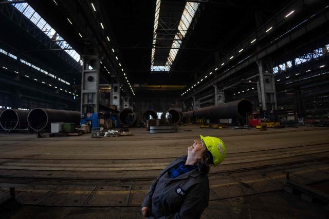 Halina Krauze, 65, a overhead crane operator, poses for a photo in the production hall of the Gdansk Shipyard in Gdansk, Poland, on March 6, 2026. "Around 70% of crane operators on construction sites today are women," Krause explains, a tradition inherited from the communist era. The shipyard, known as the birthplace of the Solidarnosc trade union that led to the fall of communism in Poland in 1989, still builds some ships but today, mainly wind turbines are produced at the site. (Photo by Wojtek RADWANSKI / AFP)