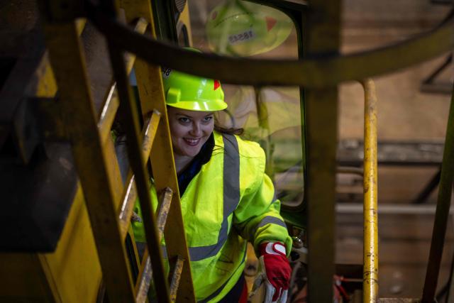 Nadia Bogomal, 37 years old Ukrainian and overhead crane operator, poses for a picture as she climbes up the ladder to the cabin of her crane in the production hall of the Gdansk Shipyard in Gdansk, Poland, on March 6, 2026. "Around 70% of crane operators on construction sites today are women," according to a worker at the shipyard, a tradition inherited from the communist era. The shipyard, known as the birthplace of the Solidarnosc trade union that led to the fall of communism in Poland in 1989, still builds some ships but today, mainly wind turbines are produced at the site. (Photo by Wojtek RADWANSKI / AFP)