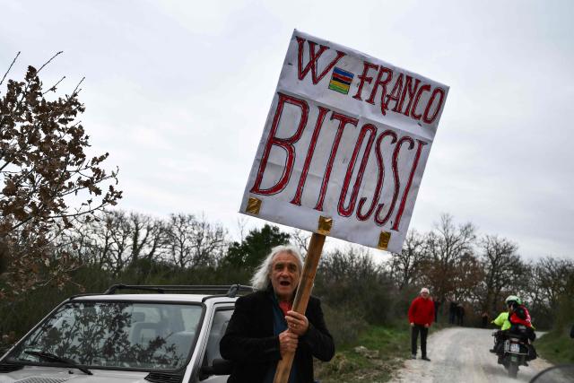 A fan holds a sign with the name of former cyclist Franco Bitossi during the 20th one-day classic 'Strade Bianche' (White Roads) men's cycling race between Siena and Siena in Tuscany on March 7, 2026. (Photo by Marco BERTORELLO / AFP)