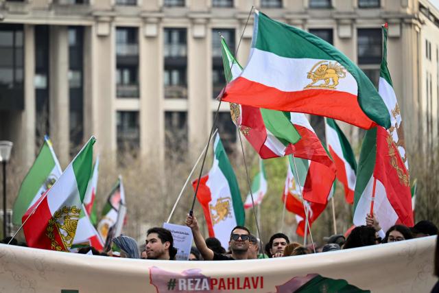 A supporter of Iran's last crown prince, now key opposition figure, Reza Pahlavi waves a Iran's pre-Islamic revolution Lion and Sun flag during a march for Iran in Paris on March 7, 2026, amid the ongoing war in the Middle East. (Photo by Lou BENOIST / AFP)