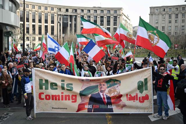 Supporters of Iran's last crown prince, now key opposition figure, Reza Pahlavi hold a banner reading "He is coming - Make Iran Great Again" and depicting a portrait of Reza Pahlavi during a march for Iran in Paris on March 7, 2026, amid the ongoing war in the Middle East. (Photo by Lou BENOIST / AFP)