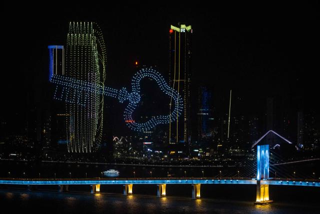 A drone display lights up the sky near the Macau Tower shorefront to mark the official end of the traditional Chinese New Year celebrations in Macau on March 7, 2026. (Photo by Eduardo LEAL / AFP)
