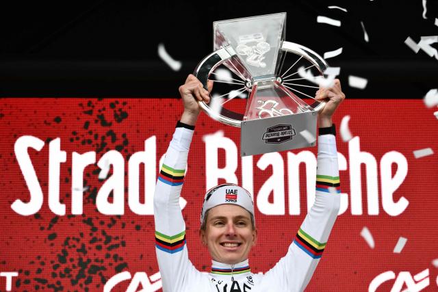 UAE Team Emirates's Slovenian Tadej Pogacar celebrates on the podium holding the Strade Bianche men's trophy after winning the 20th one-day classic 'Strade Bianche' (White Roads) men's cycling race between Siena and Siena in Tuscany on March 7, 2026. (Photo by Marco BERTORELLO / AFP)