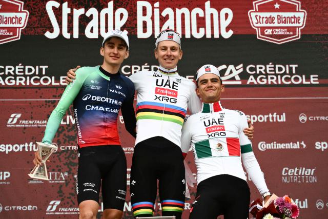 TOPSHOT - (From L) Second placed UCI WorldTeam Decathlon CMA CGM's French Paul Seixas, first placed UAE Team Emirates's Slovenian Tadej Pogacar and third placed Del UAE Team Emirates XRG's MexicanIsaac Del Toro Romero celebrate on the podium after competing in the 20th one-day classic 'Strade Bianche' (White Roads) men's cycling race between Siena and Siena in Tuscany on March 7, 2026. (Photo by Marco BERTORELLO / AFP)