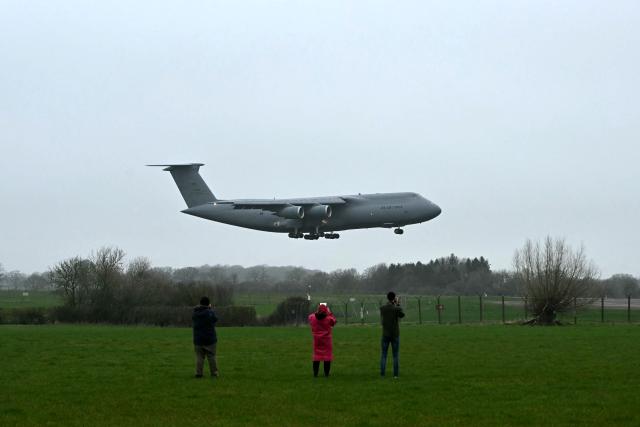 People photograph a US Air Force C-5 Galaxy landing at RAF Fairford in south west England on March 6, 2026. Britain's Prime Minister Keir Starmer finally gave his approval on March 1, for Washington to use the bases of Diego Garcia in the Indian Ocean and Fairford in southwest England to bomb Iranian missile sites, after several Gulf countries were targeted by Iranian retaliations. (Photo by JUSTIN TALLIS / AFP)
