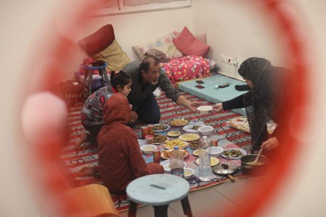 A displaced woman who lives with her family in a school's classroom after fleeing Israeli airstrikes in Beirut's southern suburbs, sit to break their fast together for the "iftar" meal in Beirut on March 7, 2026. Lebanon's social affairs minister said on March 7, that 454,000 people had been registered as displaced since the outbreak of the new war between Israel and Hezbollah. In a press briefing, Haneen Sayed said that the total number of people who registered their names on a website affiliated with the ministry reached 454,000, including 112,525 people registered in government shelters. (Photo by IBRAHIM AMRO / AFP)