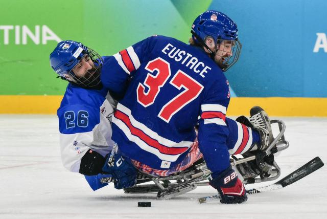 USA's David Eustace (R) fights for the puck with Italy's Eusebiu Antochi during the ice hockey match between USA and Italy at the Milano Cortina 2026 Paralympic Winter Games in Milan on March 7, 2026. (Photo by Stefano RELLANDINI / AFP)