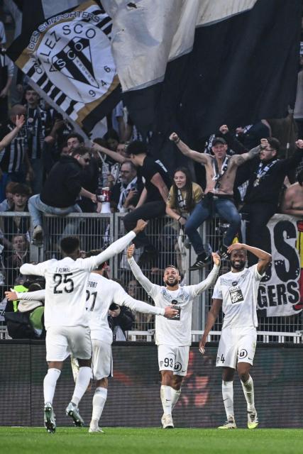 Angers' Algerian midfielder #93 Aris Belkebla (C), Angers' Haitian defender #04 Ousmane Camara (R), Angers' Ivorian defender #25 Abdoulaye Bamba (L) celebrate victory with supporters at the end of the French L1 football match between FC Nantes and SCO Angers at the Stade de la Beaujoire–Louis Fonteneau in Nantes, western France on March 7, 2026. (Photo by Sebastien Salom-Gomis / AFP)