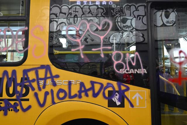 A bus covered in graffiti messages is seen during a rally on the eve of International Women's Day in Bogota on March 7, 2026. (Photo by Diana SANCHEZ / AFP)