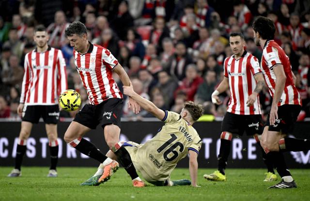 Barcelona's Spanish midfielder #16 Fermin Lopez (down) fights for the ball with Athletic Bilbao's Spanish midfielder #06 Mikel Vesga during the Spanish league football match between Athletic Club Bilbao and FC Barcelona at San Mames Stadium in Bilbao on March 7, 2026. (Photo by ANDER GILLENEA / AFP)