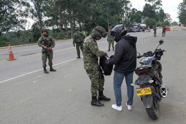 A Colombian soldier searches a motorcyclist at a roadside checkpoint on the Pan-American Highway in Tunia, Cauca department, Colombia, on the eve of the legislative elections, on March 7, 2026. Colombia will hold legislative elections on March 8 and presidential elections on May 31. (Photo by Joaquin SARMIENTO / AFP)